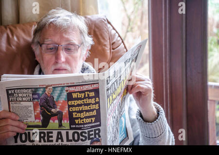 A man sits in Ann armchair reading the Daily Mail newspaper Stock Photo