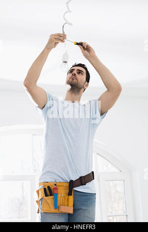 Mid-adult man fixing light bulb wiring in new house Stock Photo