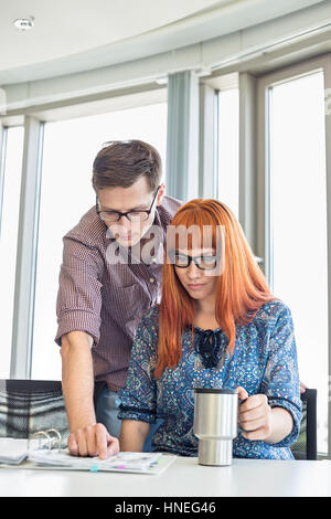 Businesspeople reading file together at desk in creative office Stock Photo