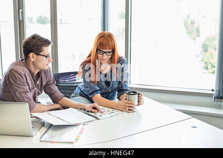 Creative business colleagues reading file together at desk in office Stock Photo