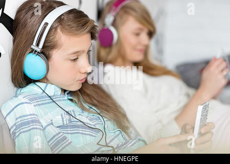 Sisters listening music through headphones at home Stock Photo