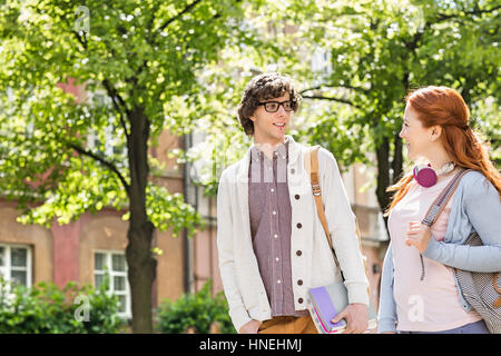 Young male and female college students talking while walking on street Stock Photo