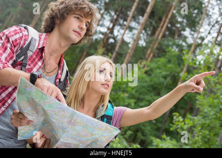 Hiking couple with map discussing over direction in forest Stock Photo