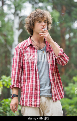 Young man smoking in forest Stock Photo