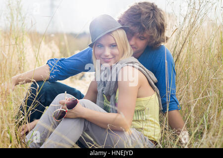 Smiling woman sitting with loving man in field Stock Photo