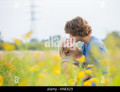 Romantic man kissing woman in field Stock Photo