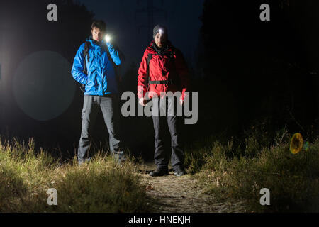 Full length portrait of male hikers with flashlights in field at night Stock Photo