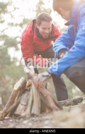 Male hikers lighting bonfire in forest Stock Photo
