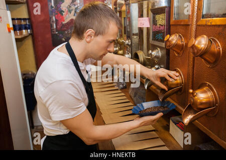 Side view of salesperson dispensing coffee beans into bowl at store Stock Photo