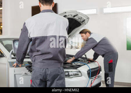 Male maintenance engineers examining car in workshop Stock Photo