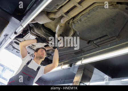 Low angle view of male automobile mechanic repairing car in repair shop Stock Photo