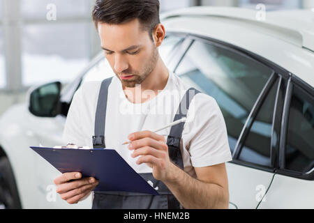 Young male maintenance engineer holding clipboard in repair shop Stock Photo