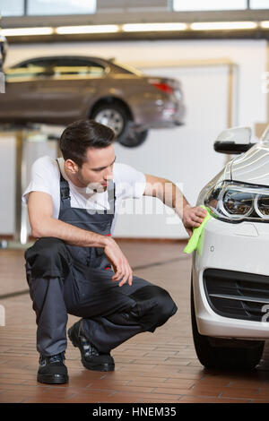 Full length of automobile mechanic cleaning car in workshop Stock Photo