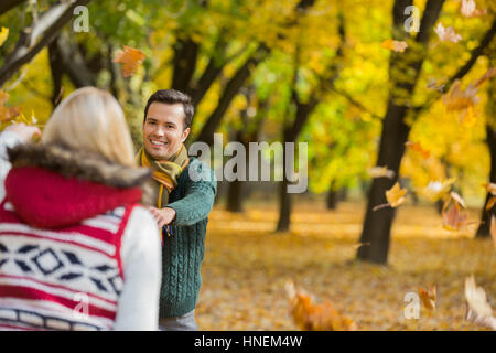 Happy couple playing with autumn leaves in park Stock Photo
