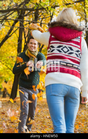 Happy young couple playing with autumn leaves in park Stock Photo