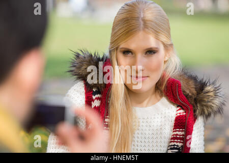 Beautiful young woman being photographed by man in park Stock Photo