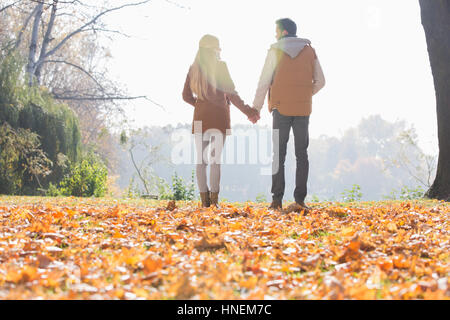 Rear view of couple holding hands in park during autumn Stock Photo