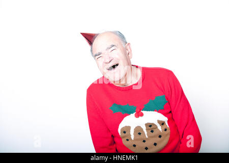 Senior adult man wearing a Christmas jumper and a red party hat Stock Photo