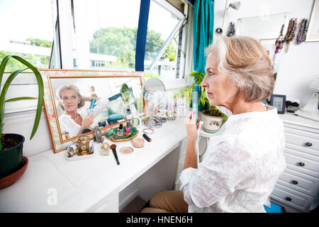 Senior woman combing her hair at dresser in house Stock Photo