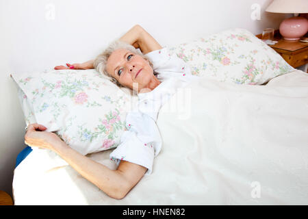High angle view of senior woman looking away while lying in bed at home Stock Photo