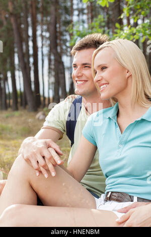 Thoughtful hiking couple looking away while relaxing in forest Stock Photo