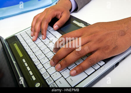 Close up of Indian mans hands typing on laptop Stock Photo