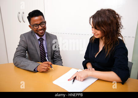 Multi-ethnic work colleagues looking at paperwork on a table Stock Photo