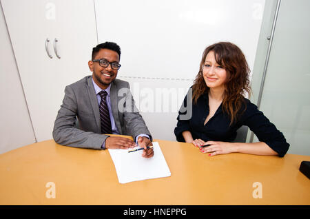 Multi-ethnic work colleagues signing paperwork on a table Stock Photo