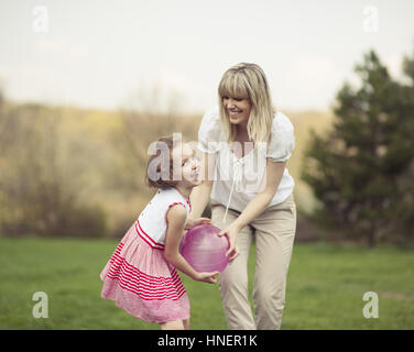 Mother and daughter playing with ball in the park Stock Photo