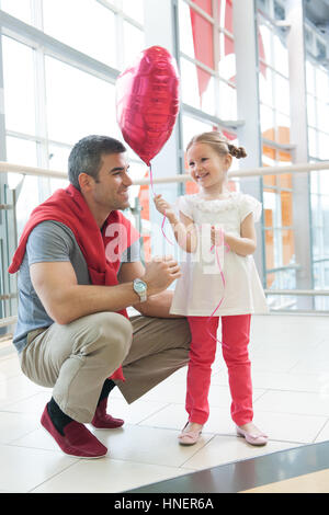 Father gives young daughter heart shaped balloon Stock Photo