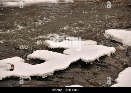Close up of water running through partially frozen creek. Stock Photo