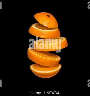 Flying orange. Sliced orange isolated on black background. Levity fruit floating in the air. Stock Photo