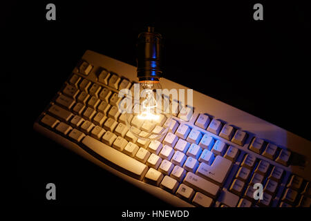 Light bulb and computer keyboard, concept of wisdom. Stock Photo