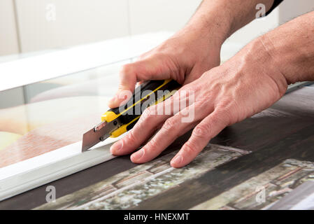 Close-up hands of male professional cutting wide format prints using utility knife cutter Stock Photo