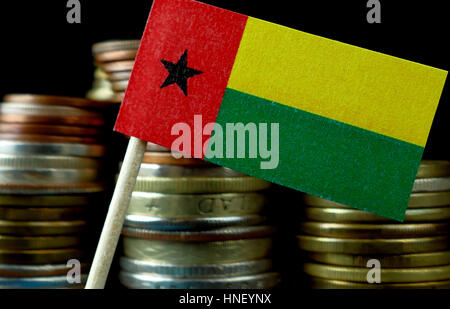 Guinea Bissau flag waving with stack of money coins macro Stock Photo