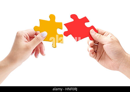 hands of a male and female putting together two matching jigsaw pieces, isolated on white background. Stock Photo