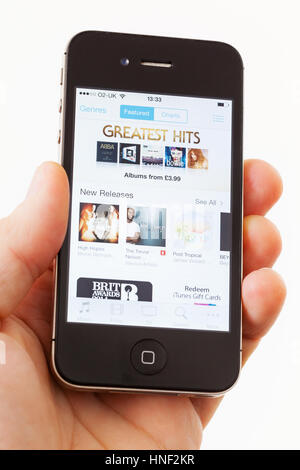 BATH, UK - JANUARY 15, 2014: A man's hand holding an Apple iPhone 4s which is displaying the front page of the Apple iTunes store. Shot in close-up ag Stock Photo