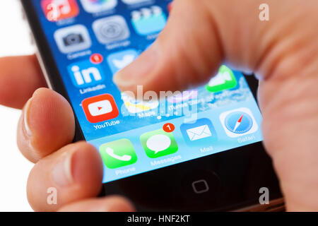 BATH, UK - JANUARY 15, 2014: Close-up of  an Apple iPhone 4s  screen with a man's thumb hovering above the text message icon which shows one unread me Stock Photo