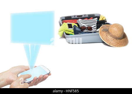 Female hands holding a smart phone radiating a transparent rectangle. Suitcase packed with clothes is in the background. Everything is on a white back Stock Photo