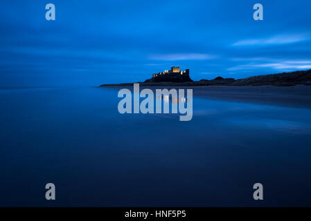 Bamburgh Castle lit up in the pre-dawn light on the Northumberland Coast. Stock Photo
