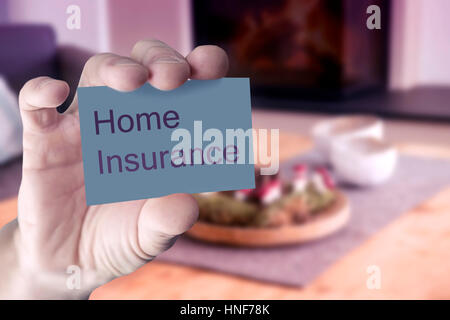 closeup of mans hand showing business card with the words Home Insurance in front of living room Stock Photo