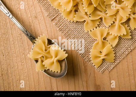 raw farfalle bow-tie pasta on wooden table Stock Photo