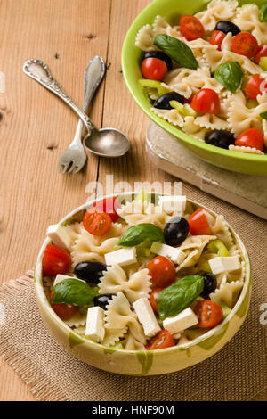 rustic farfalle salad in bowl on wooden table Stock Photo