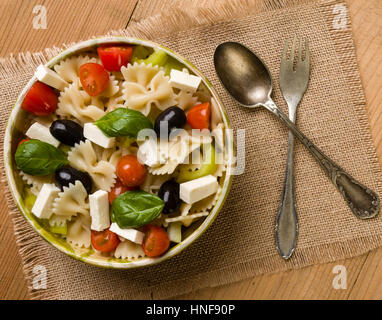 rustic farfalle salad in bowl on wooden table Stock Photo