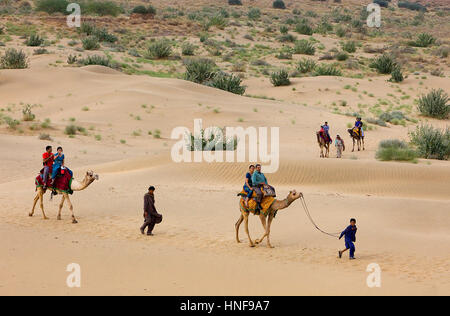 Tourists riding camels on Sam dunes in Desert National Park in the Great Thar Desert,near Jaisalmer, Rajasthan, India