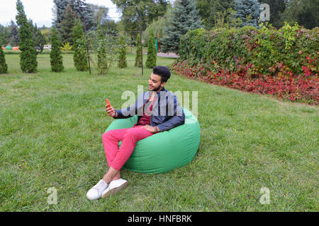 Young Handsome Man Arab Businessman, Student Holding Mobile Phone, Gadget and Calls, Communicates on Skype For Video Calling, Smiling and Sitting in C Stock Photo