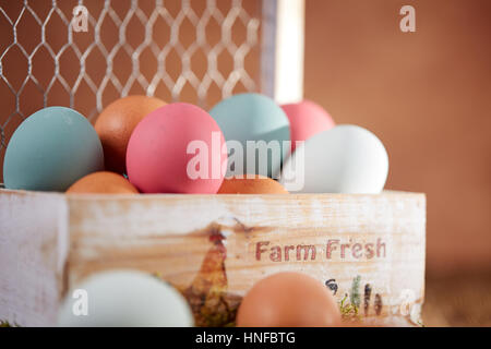 Colored pastel easter eggs in wooden box and on green moss on a wooden talbe Stock Photo