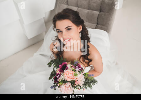 Beautiful bride posing in her wedding day with flower bouquet Stock Photo