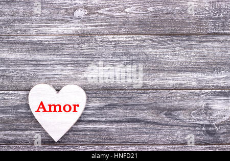 Decorative white wooden heart on grey wooden background with lettering Love in Portuguese. Valentines day card. Wedding Stock Photo