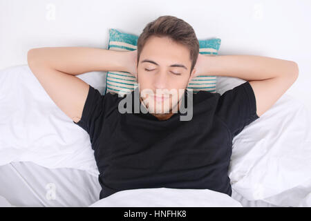 Close-up of attractive young man sleeping on her bed. Indoors. Stock Photo